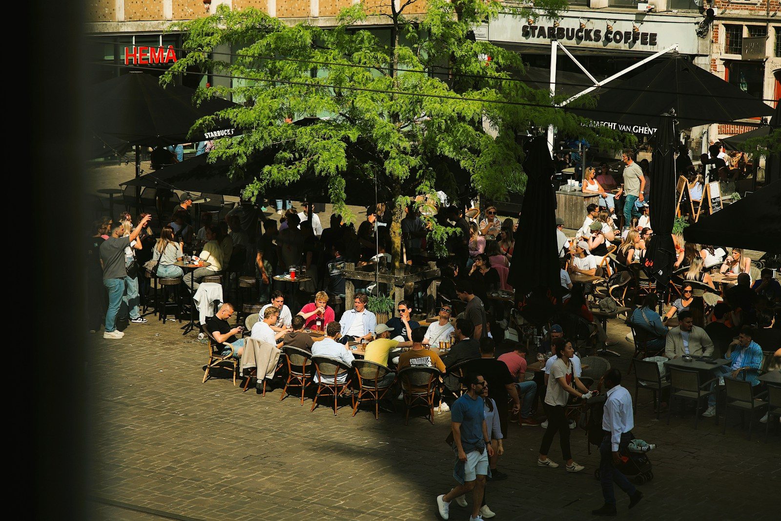 Café ao ar livre lotado de pessoas aproveitando um dia de sol