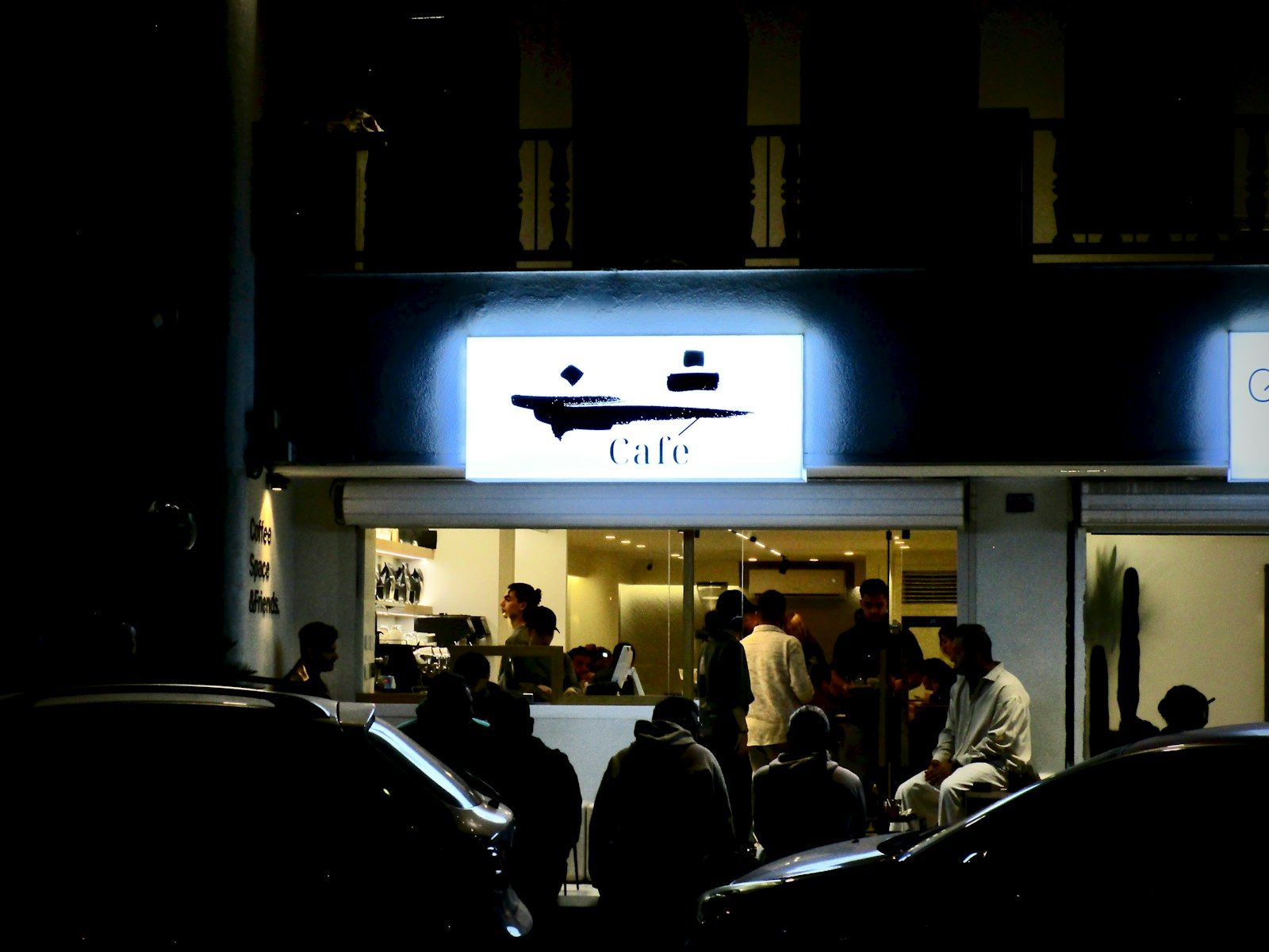 Pessoas reunidas em frente a um café à noite