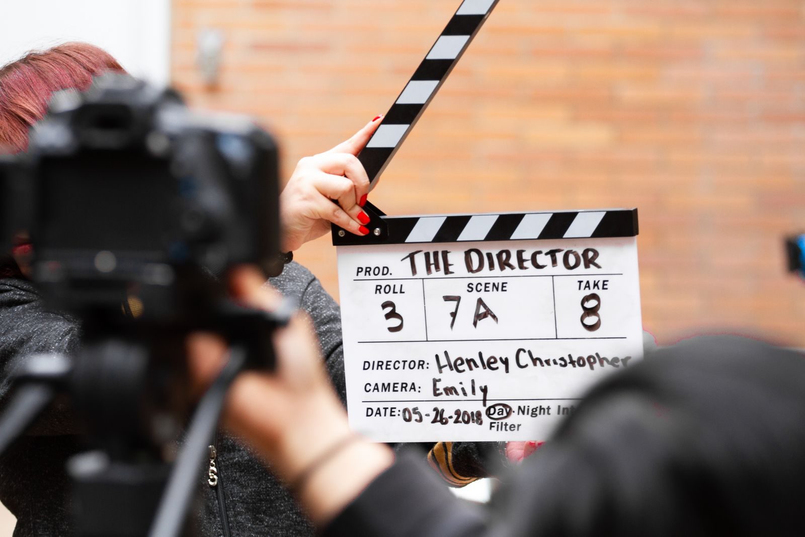 Close de uma claquete em ação com uma câmera filmando uma tomada no set