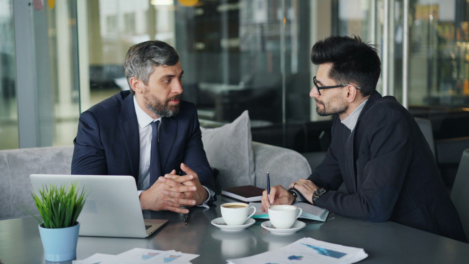 Dois homens sentados à mesa conversando