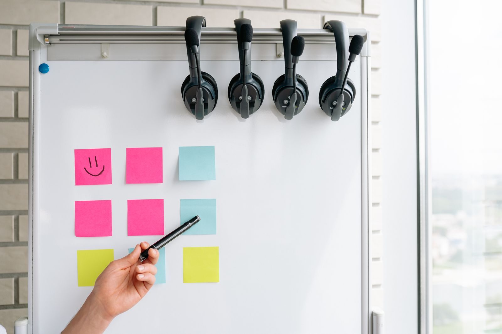 Quadro branco com post-its e fones de ouvido pendurados em ambiente de escritório