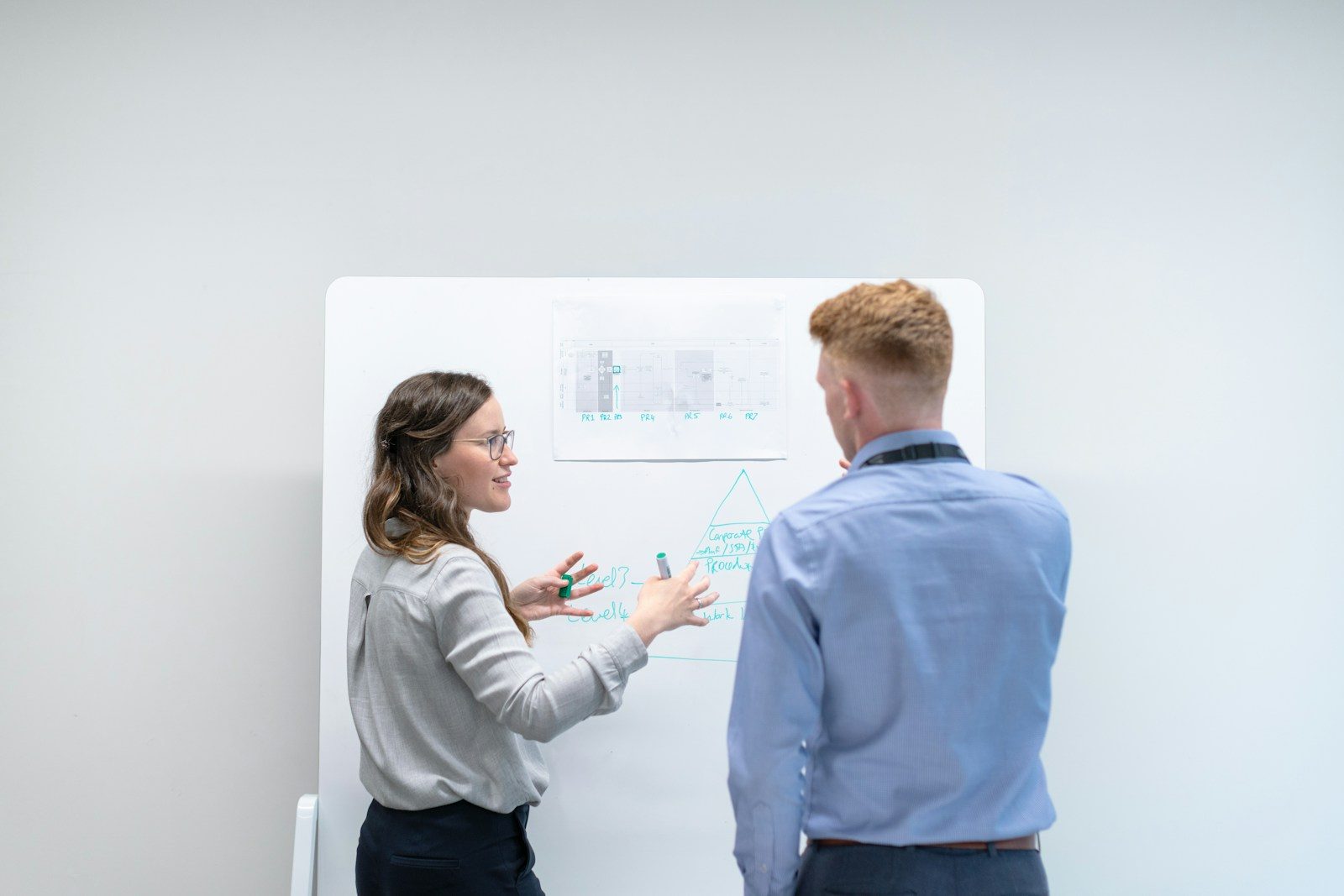 Dois colegas discutindo ideias diante de um quadro branco