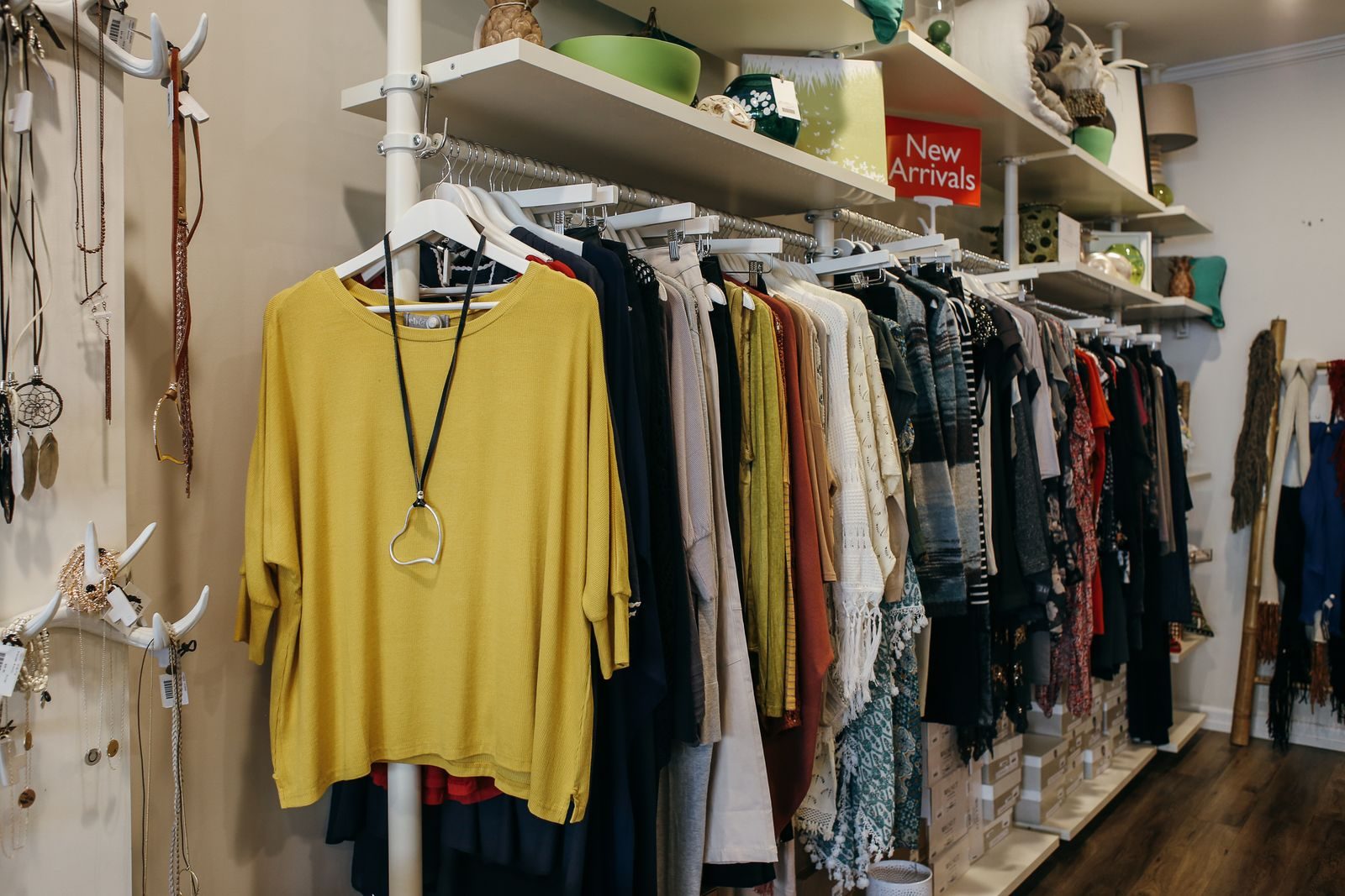 Interior de uma boutique de moda com roupas expostas com elegância em araras e prateleiras