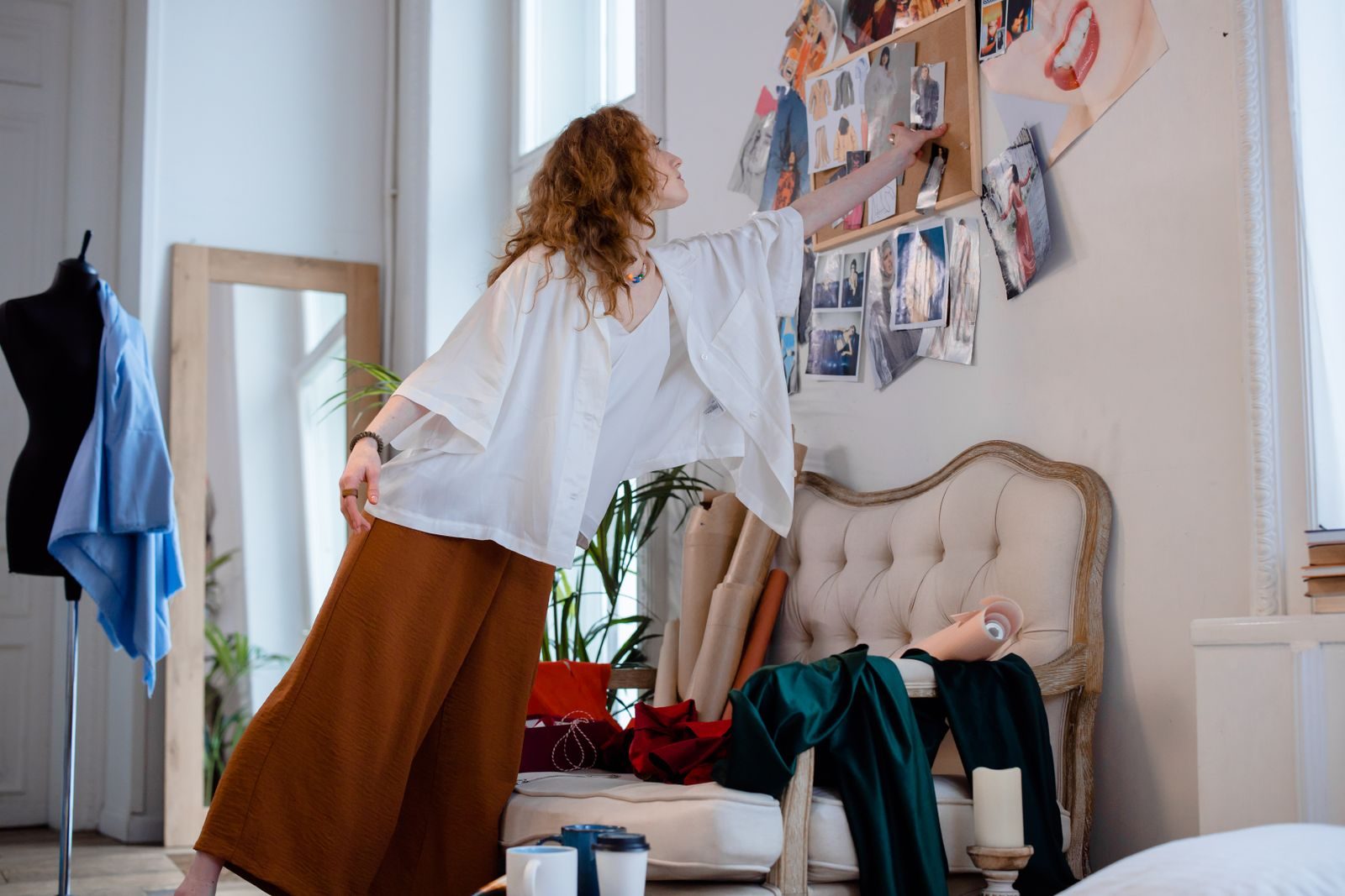 Estilista organizando esboços e materiais em um estúdio elegante e criativo