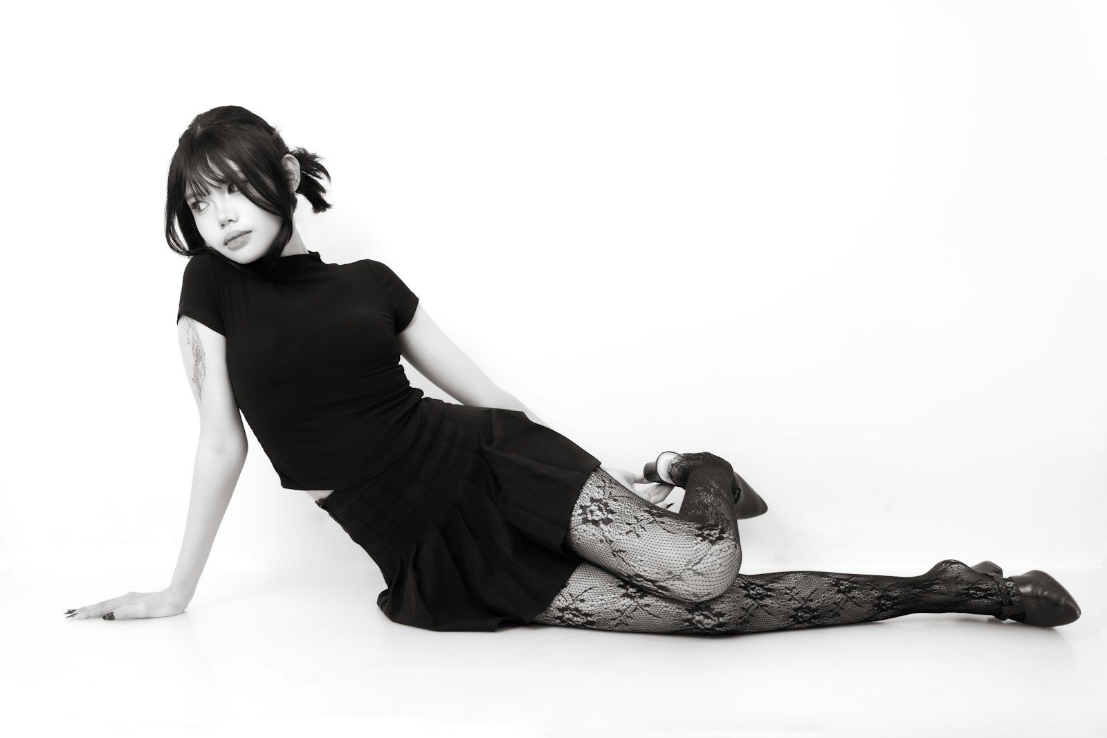 Mulher de vestido preto e meia-calça estampada posando