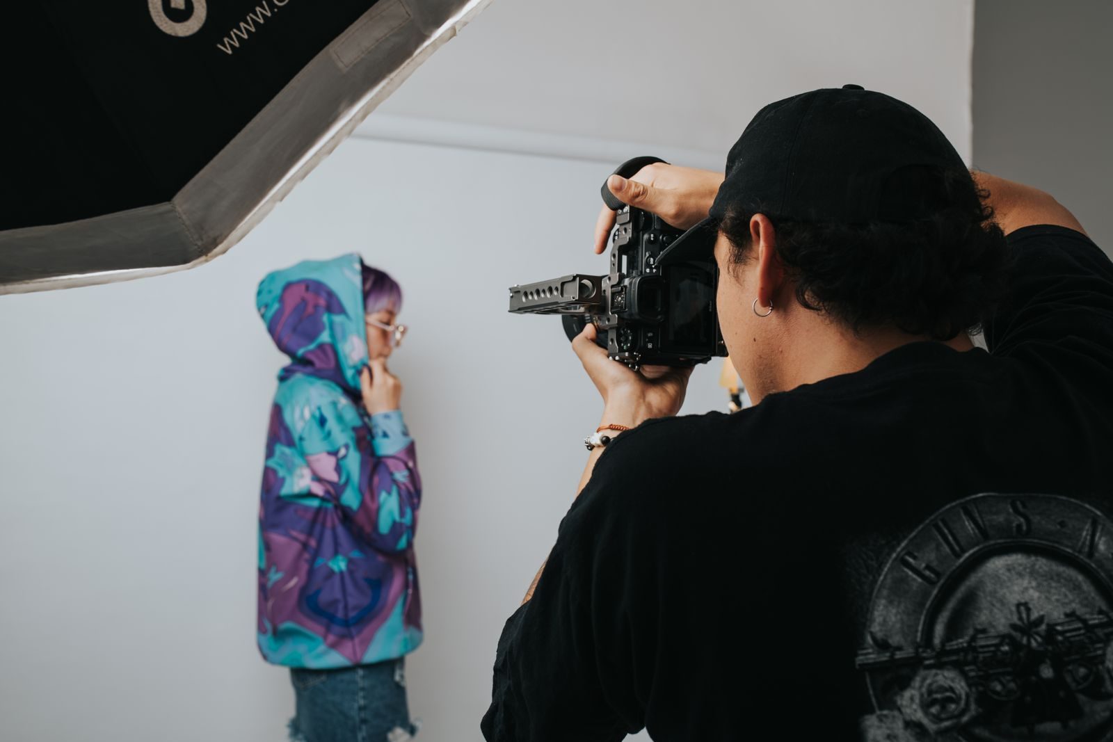 Fotógrafo fotografando uma modelo em estúdio vibrante com equipamento profissional