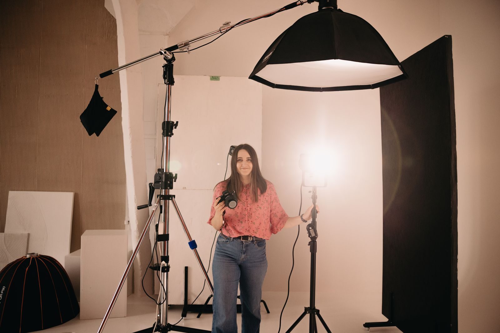 Fotógrafa segurando câmera em estúdio bem iluminado com equipamento profissional