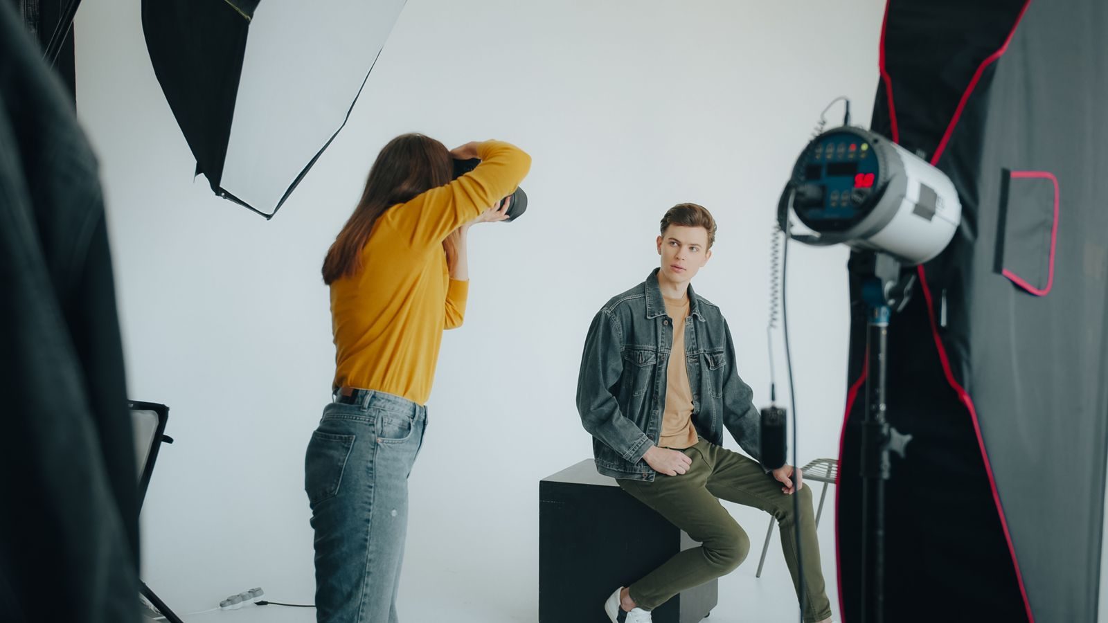 Fotógrafo fotografando modelo masculino em estúdio moderno com equipamentos de iluminação