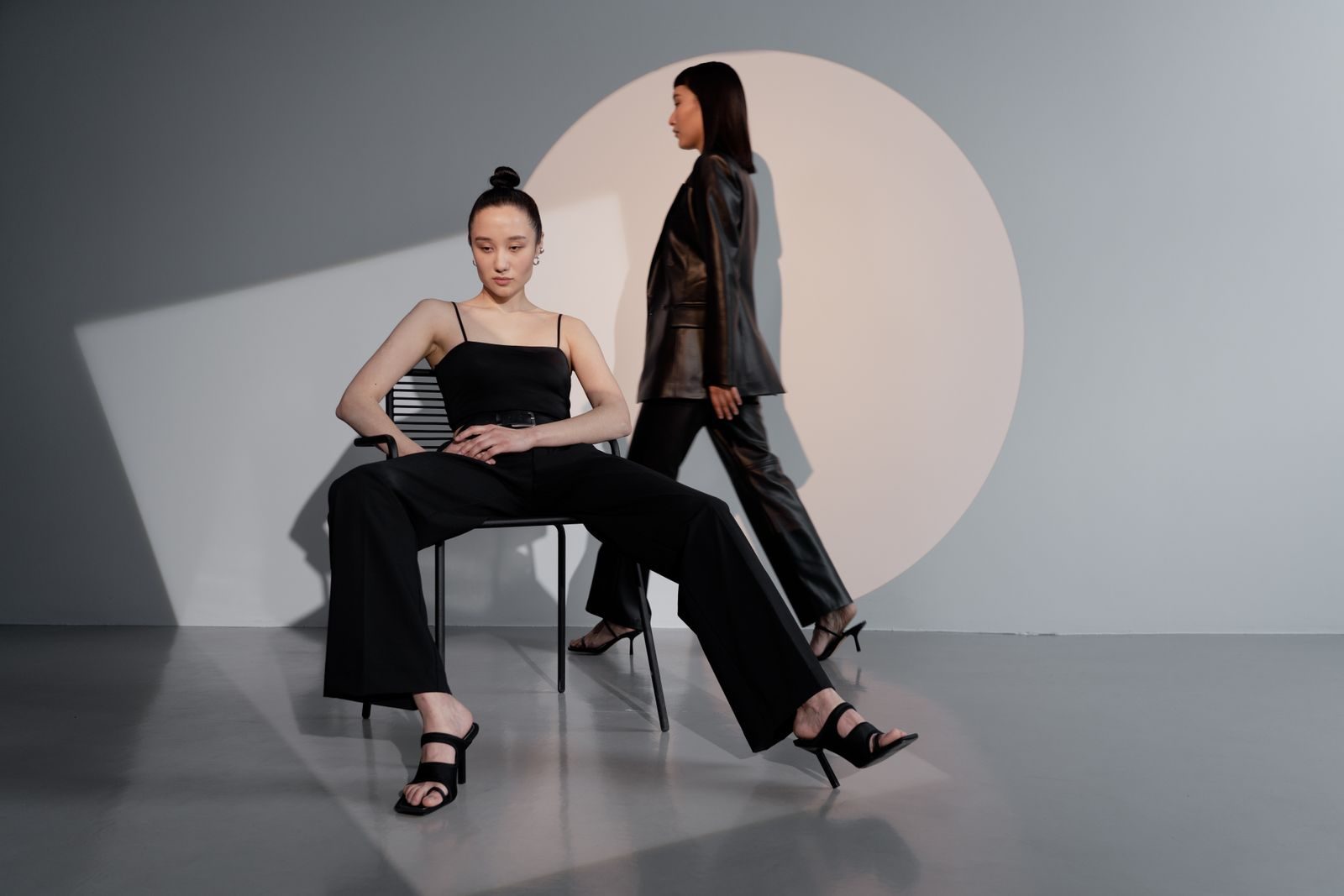 Modelos elegantes posando em estúdio moderno com iluminação dramática e moda sofisticada
