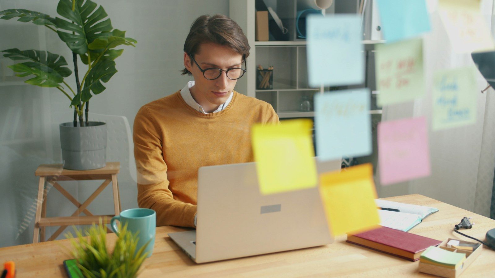 Homem trabalhando no notebook com post-its