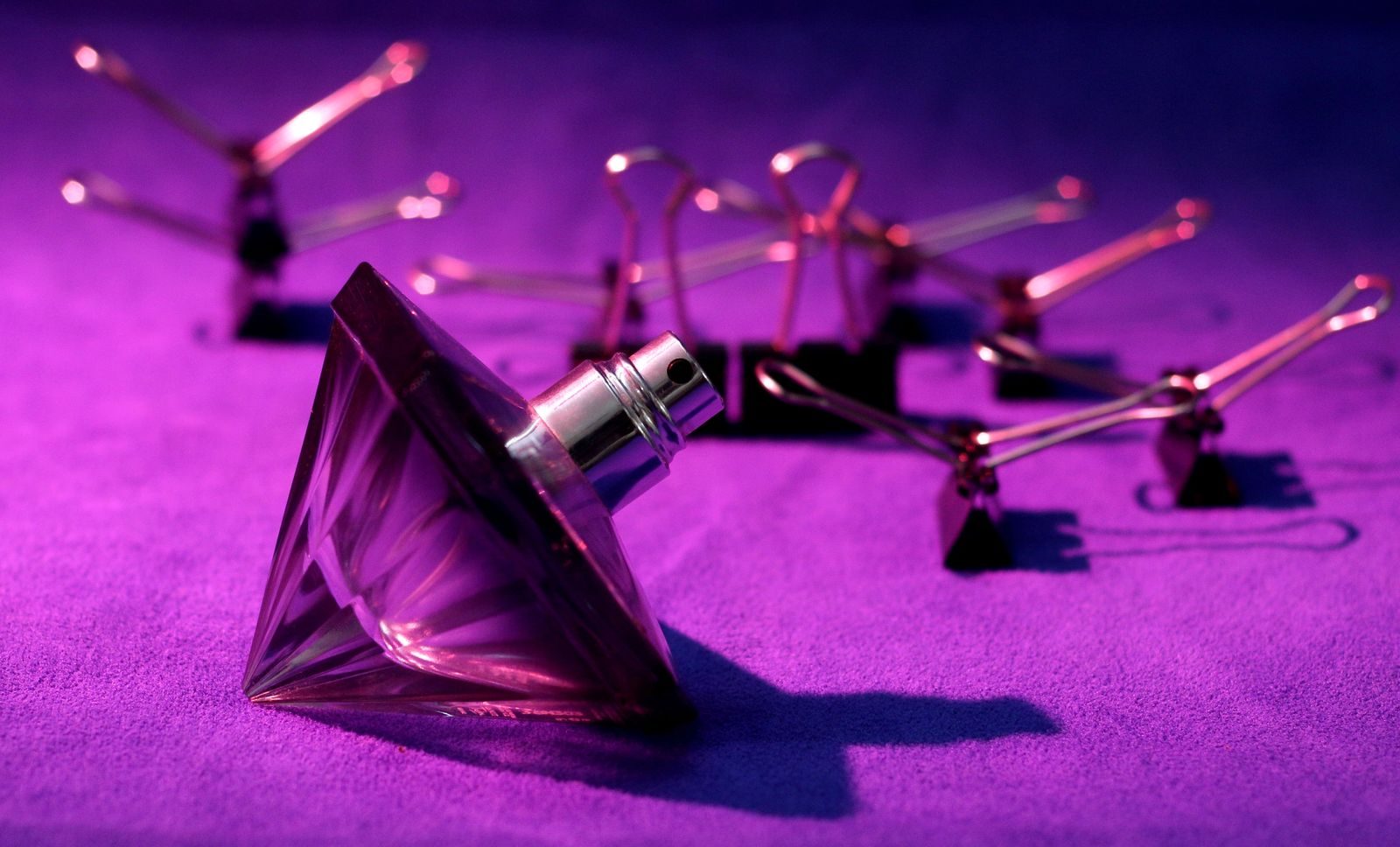 Close de frasco de perfume com design luxuoso sobre fundo roxo