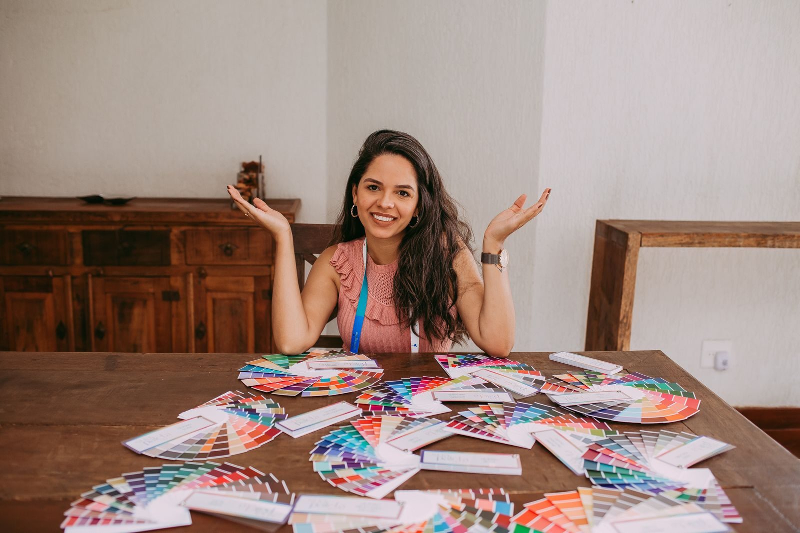 Mulher sorridente sentada a uma mesa repleta de amostras coloridas