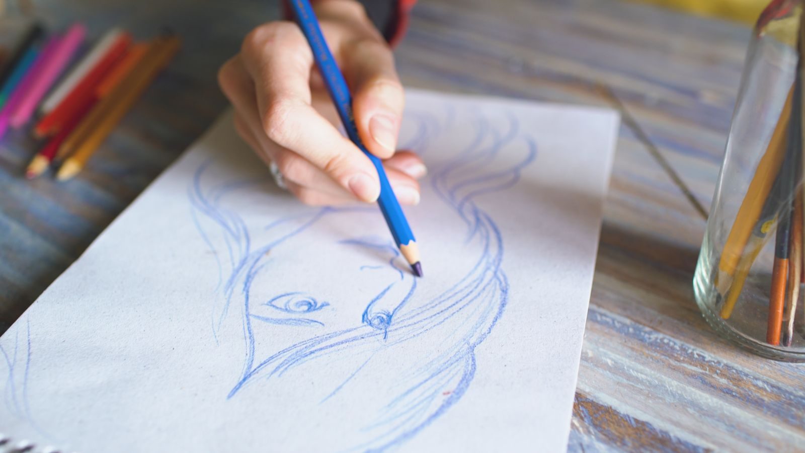 Close de mão desenhando um retrato com lápis de cor no papel