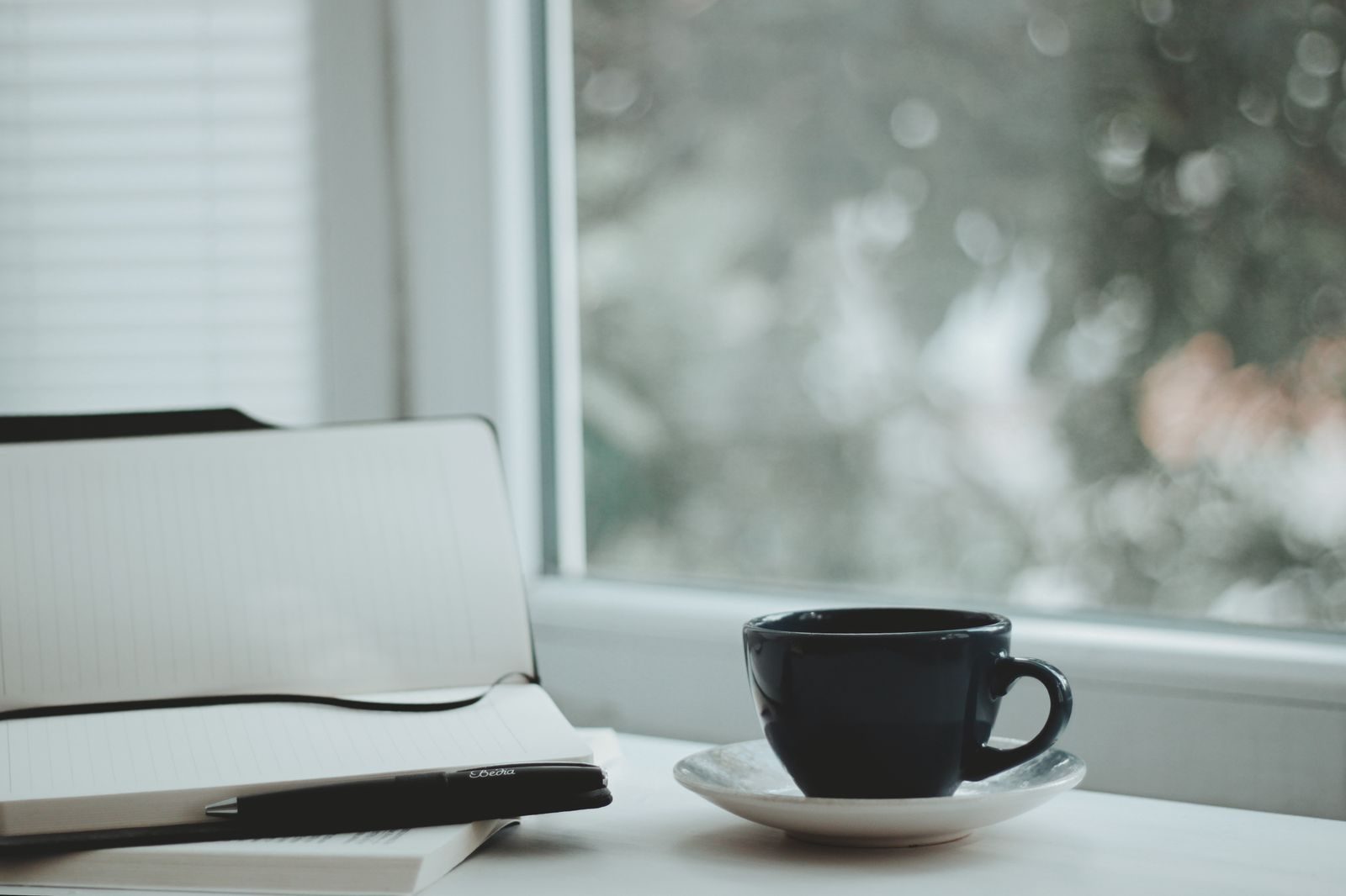 Cena serena com xícara de café e caderno perto da janela, ideal para manhãs calmas