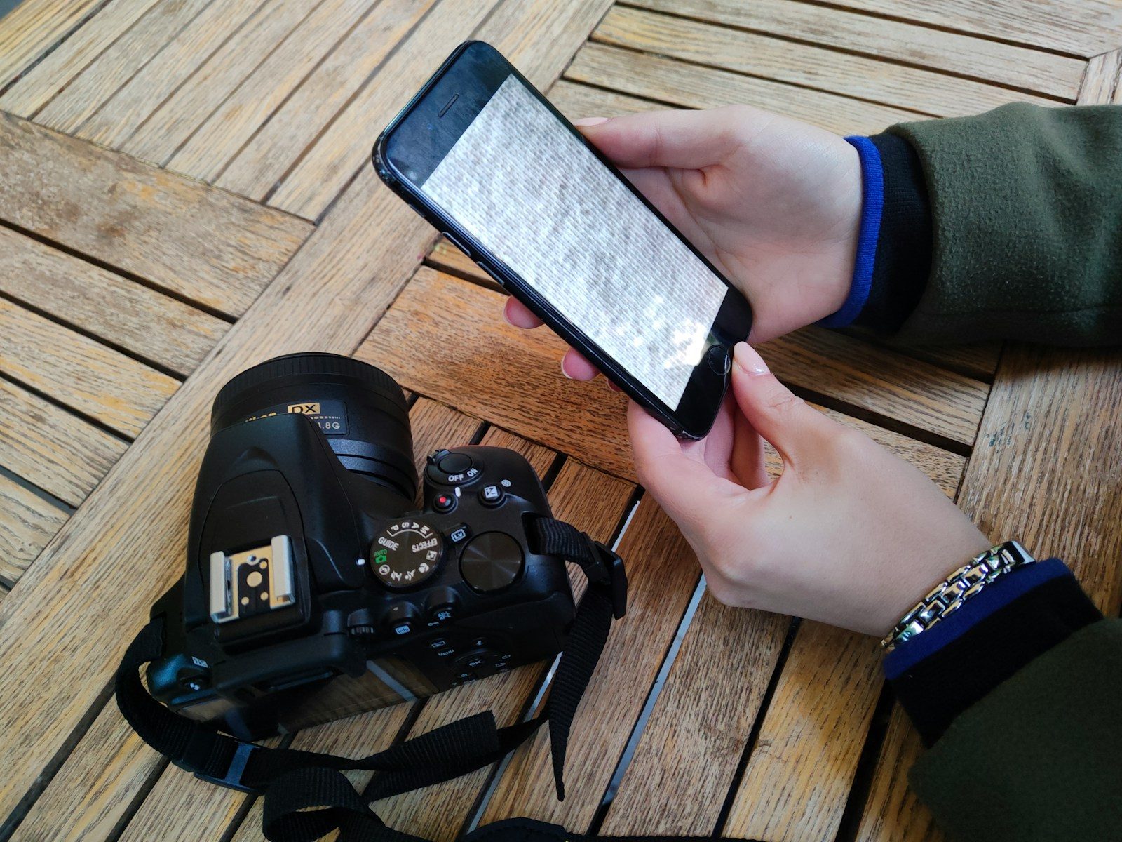 Pessoa segurando um celular acima de uma câmera