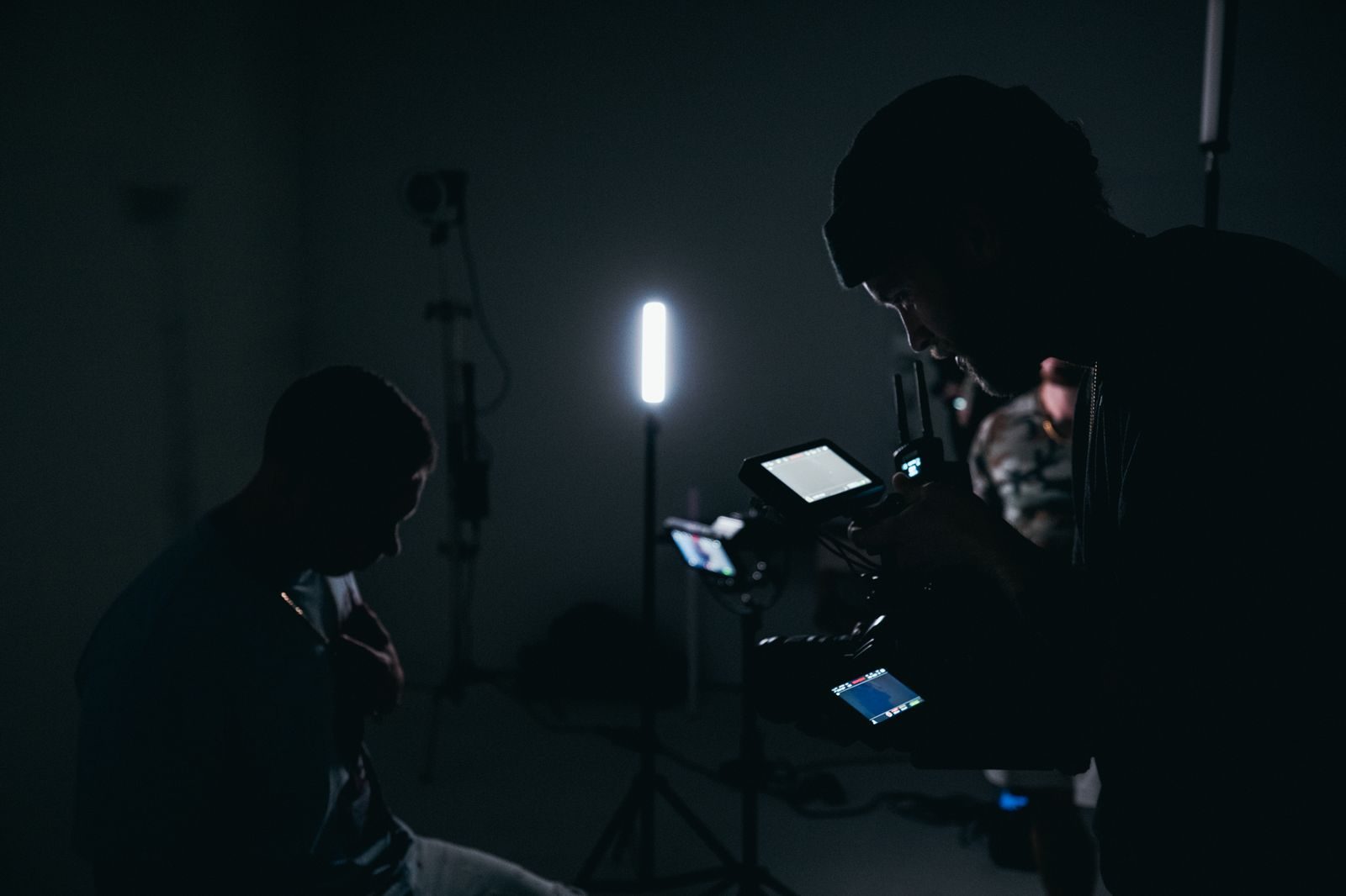 Estúdio com pouca luz e um diretor de fotografia operando uma câmera com equipamento de iluminação