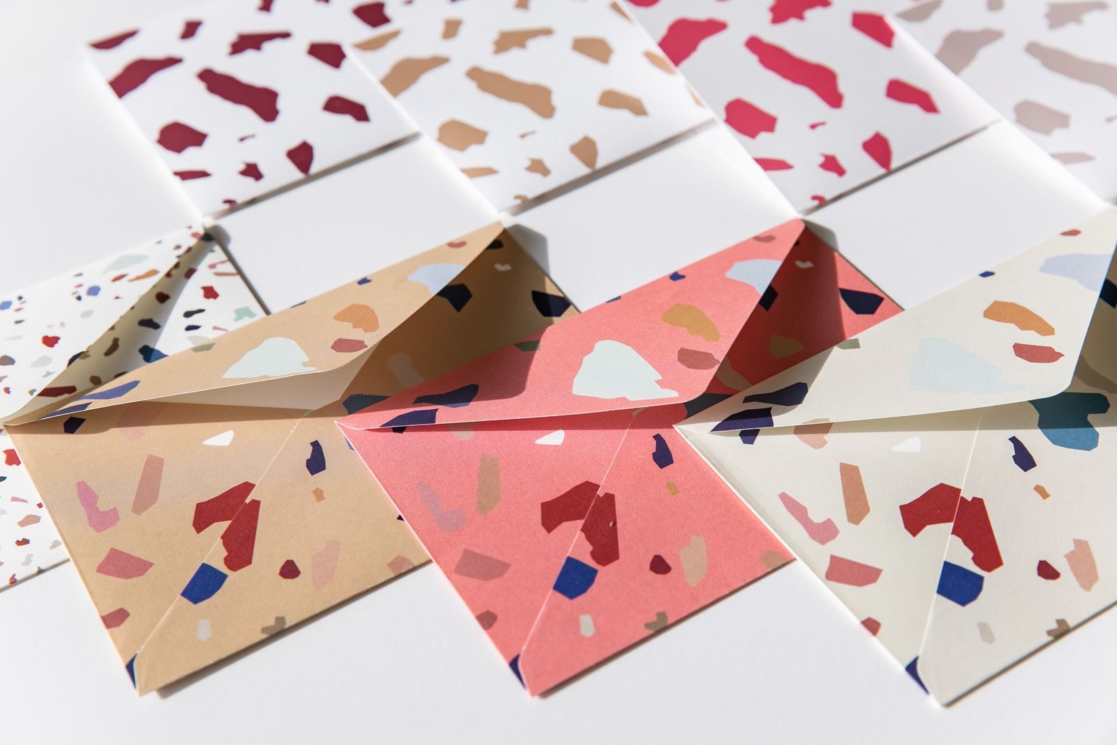 Flat lay de envelopes coloridos com estampa terrazzo sob luz natural