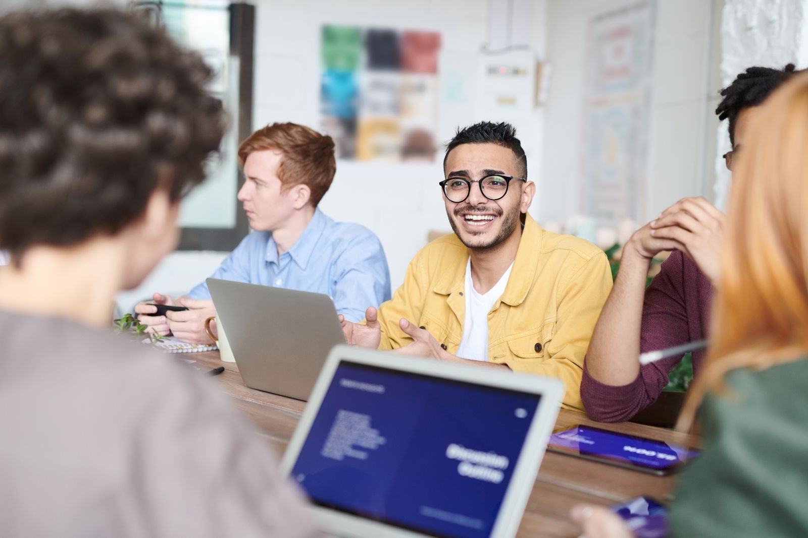 Grupo diverso discutindo um projeto com notebooks em sala de reunião moderna