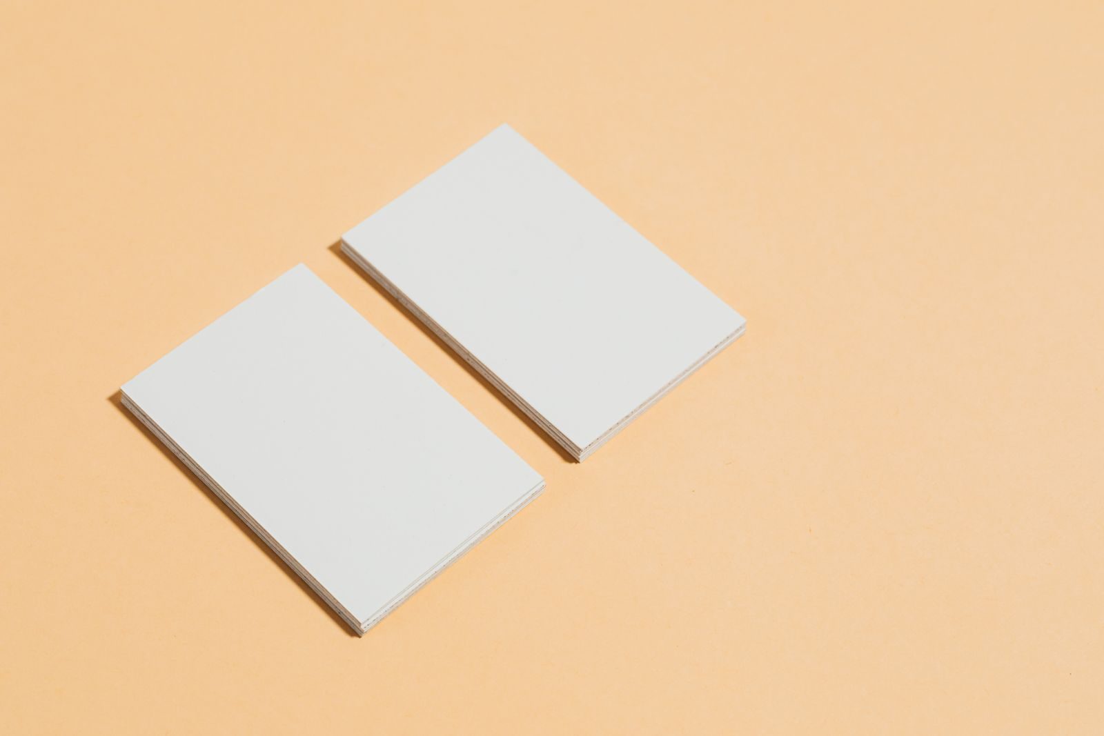 Close de cartões de visita brancos em branco sobre fundo laranja pastel, ideal para mockups