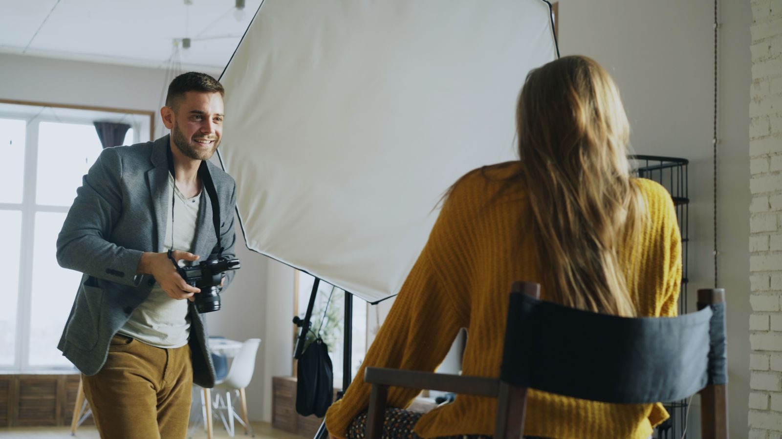 Fotógrafo fotografando modelo em ambiente interno com iluminação para retratos profissionais