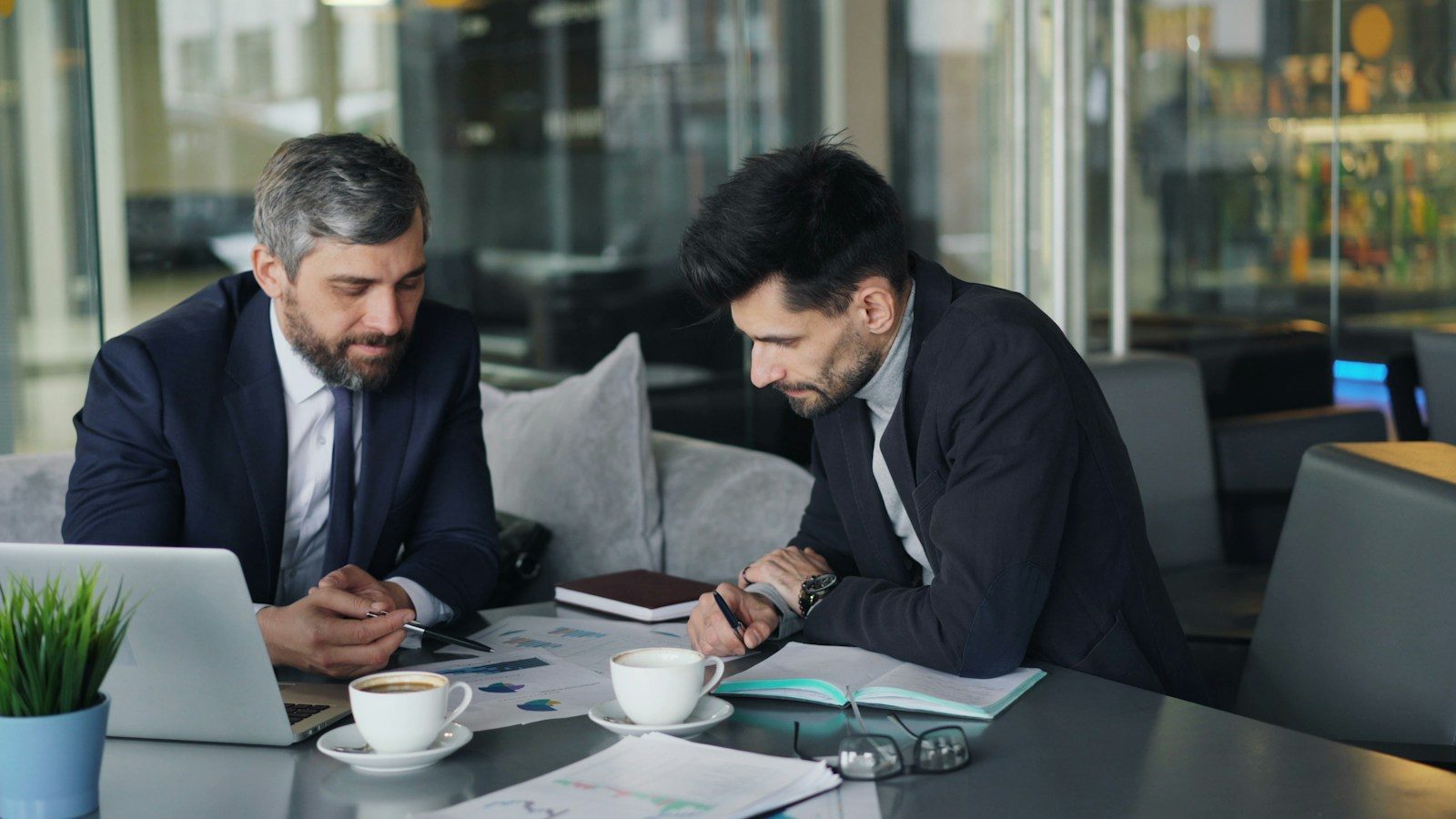 Dois homens sentados à mesa trabalhando em um notebook