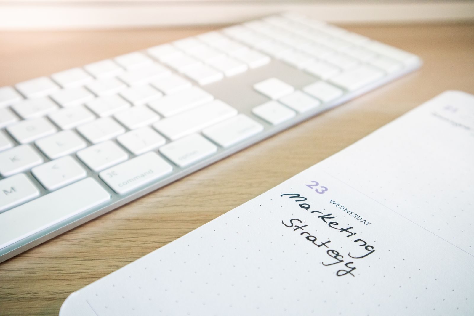 Caderno com anotação de estratégia de marketing ao lado de um teclado em uma mesa de madeira