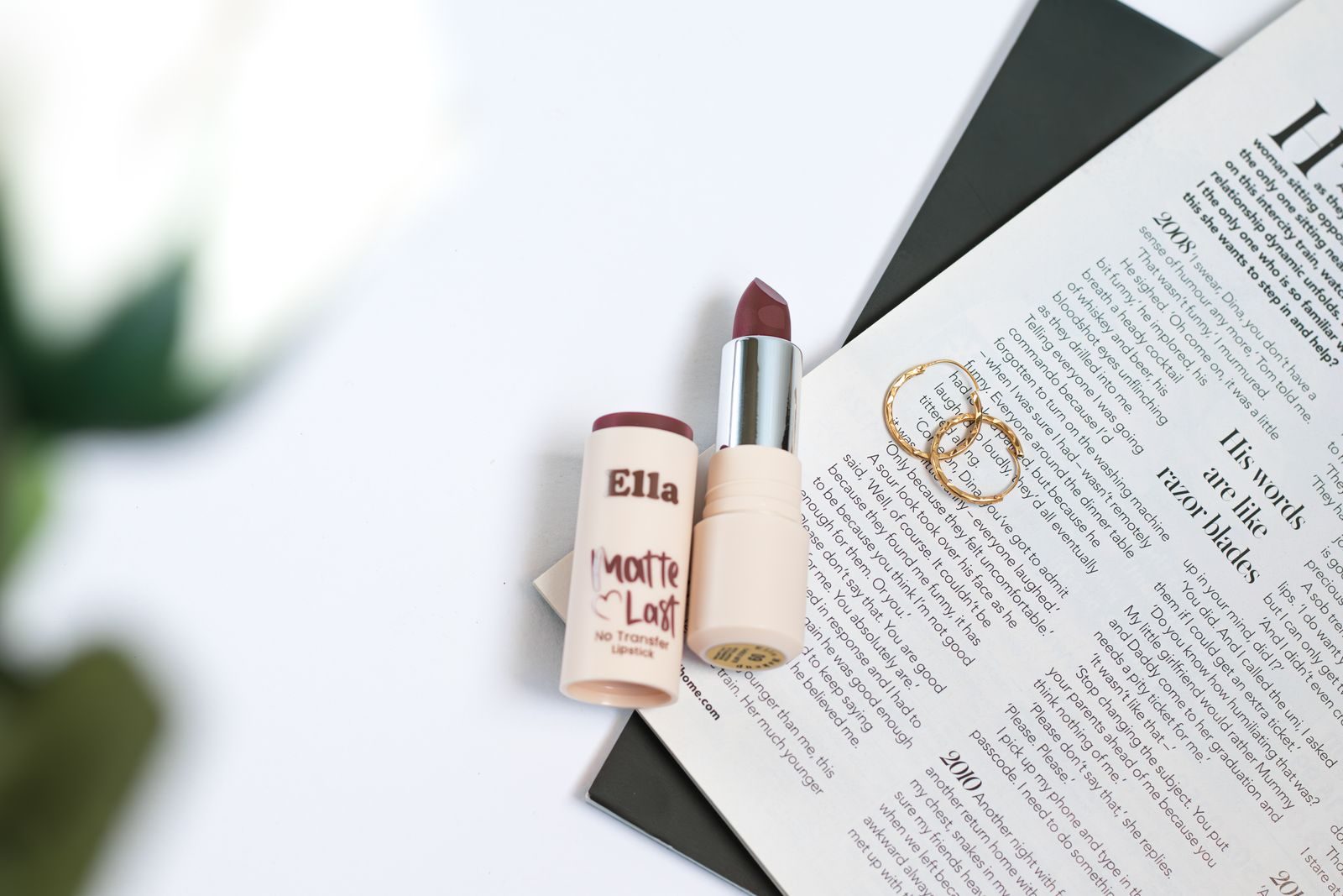 Flat lay com batom, brincos e revista