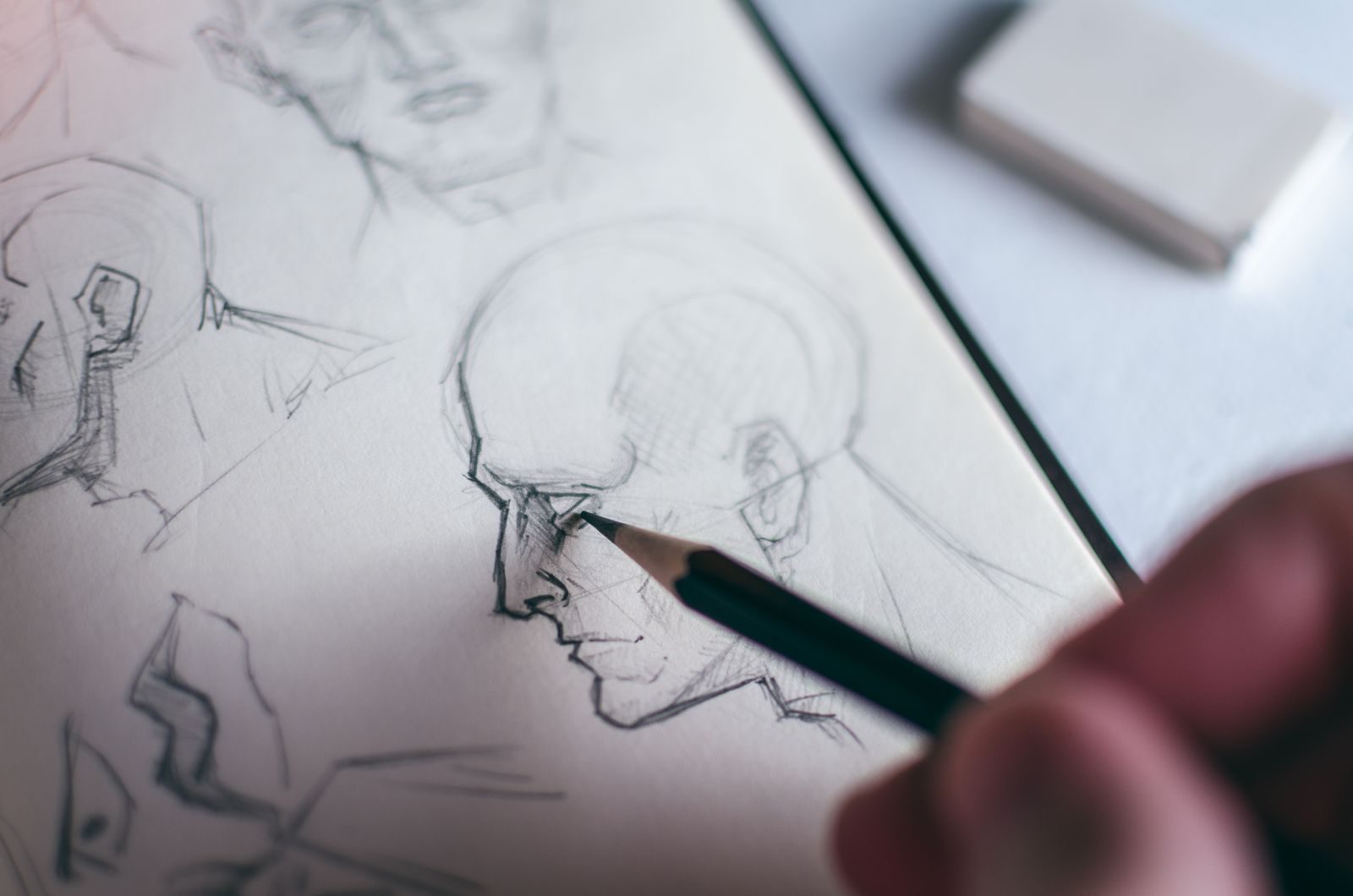 Mão desenhando um rosto humano em um caderno de esboços