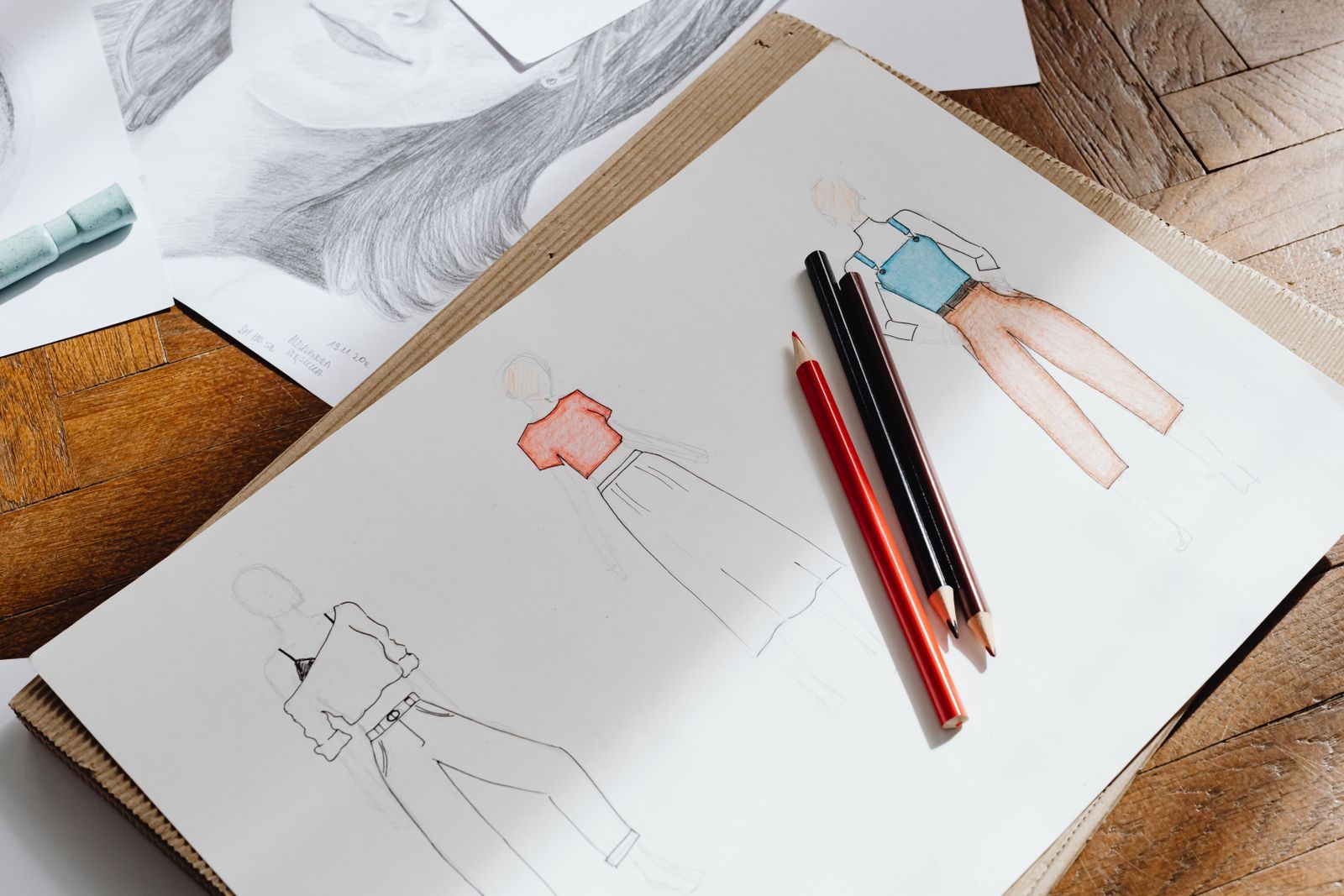 Croquis de moda em papel com lápis de cor sobre superfície de madeira
