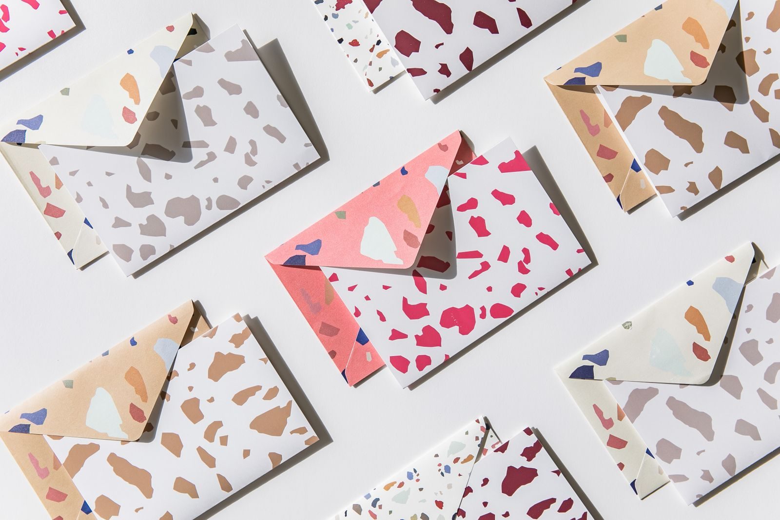 Flat lay de envelopes coloridos com estampa granilite sobre superfície branca