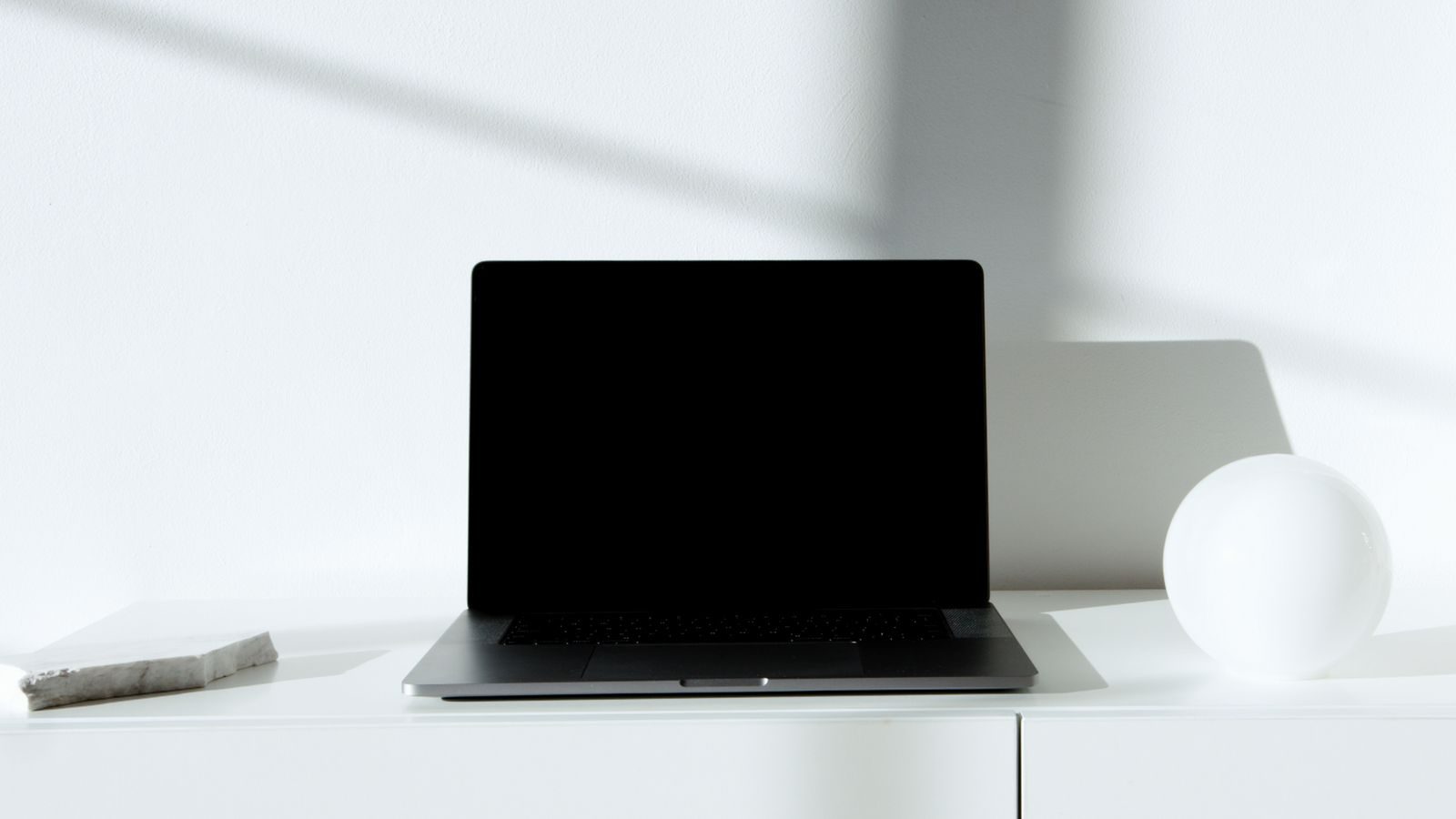 Notebook preto elegante em mesa branca, em ambiente minimalista com luz natural