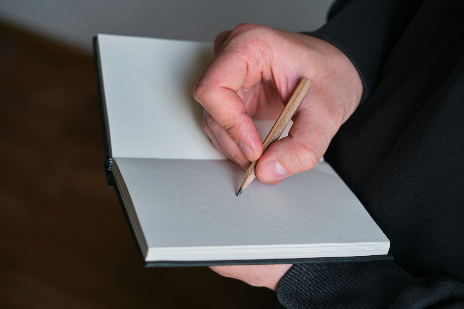 Mão segurando lápis e escrevendo em um caderno