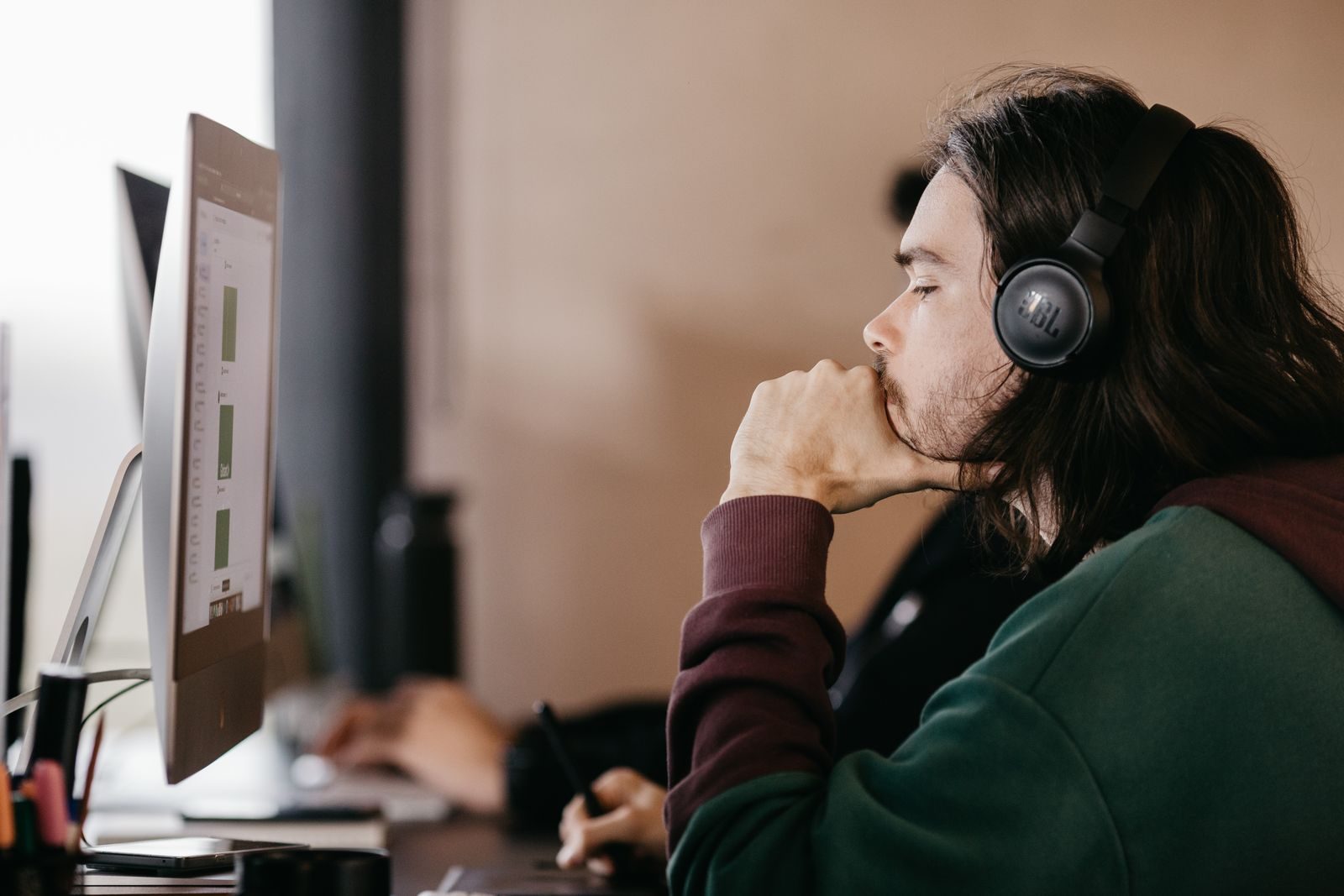 Jovem de fones de ouvido concentrado no computador em um escritório moderno