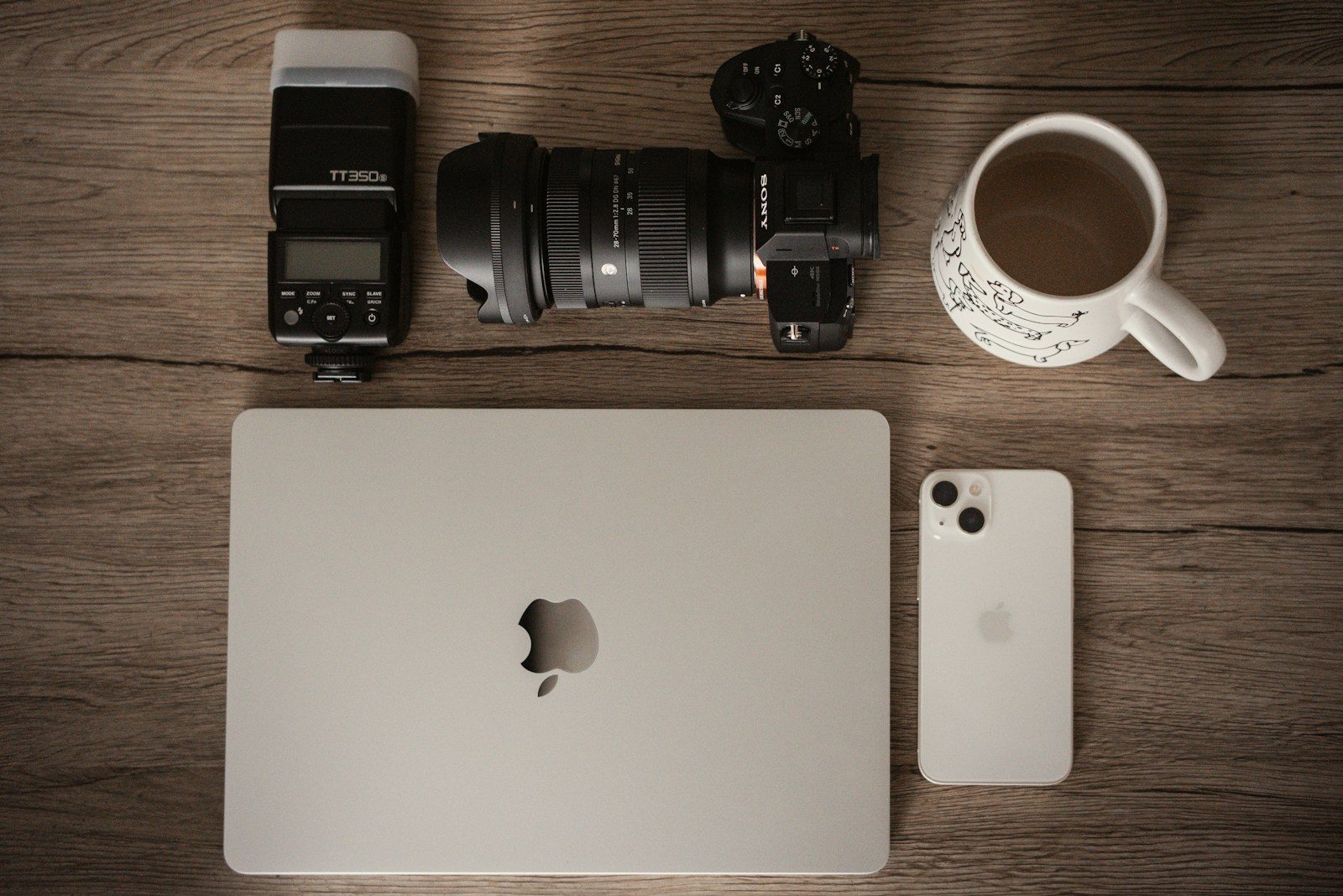 Câmera, notebook, celular e café em mesa de madeira