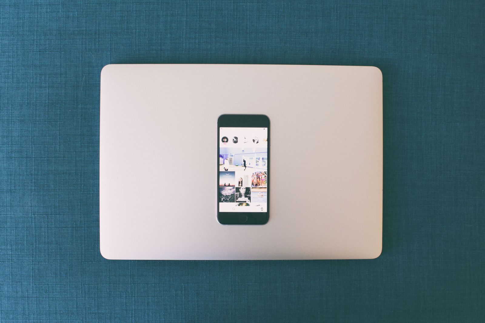 Flat lay de smartphone sobre notebook com fotos de redes sociais na tela