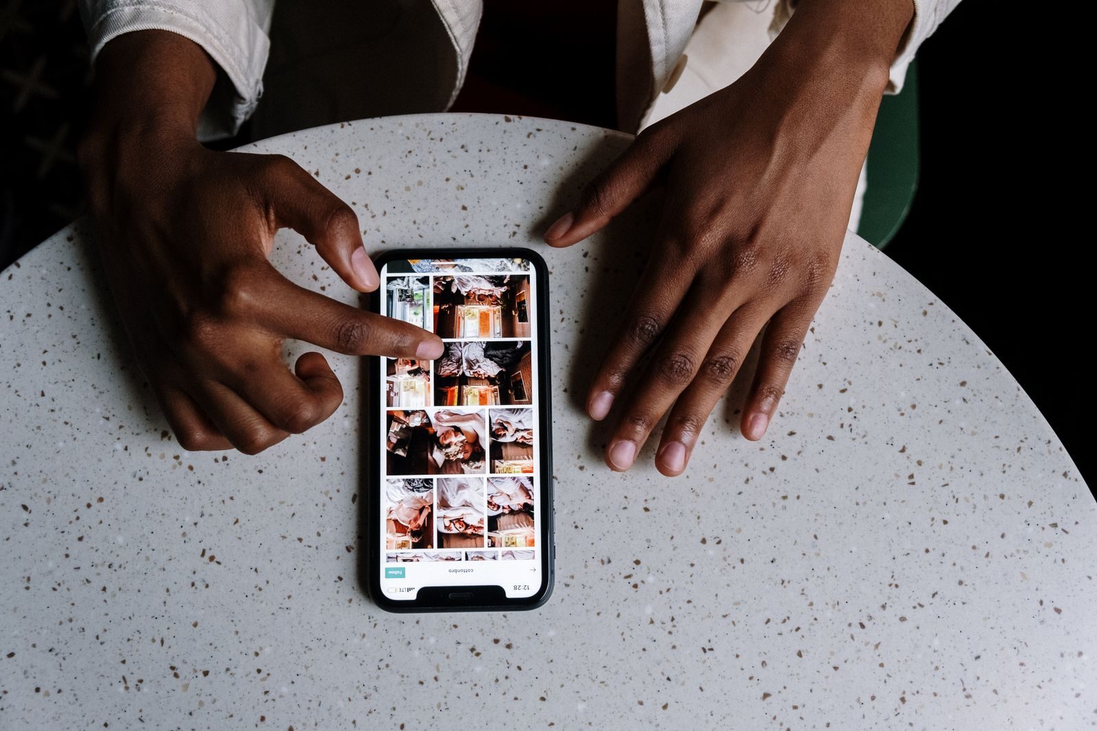 Mãos usando smartphone com conteúdo de redes sociais em mesa de café
