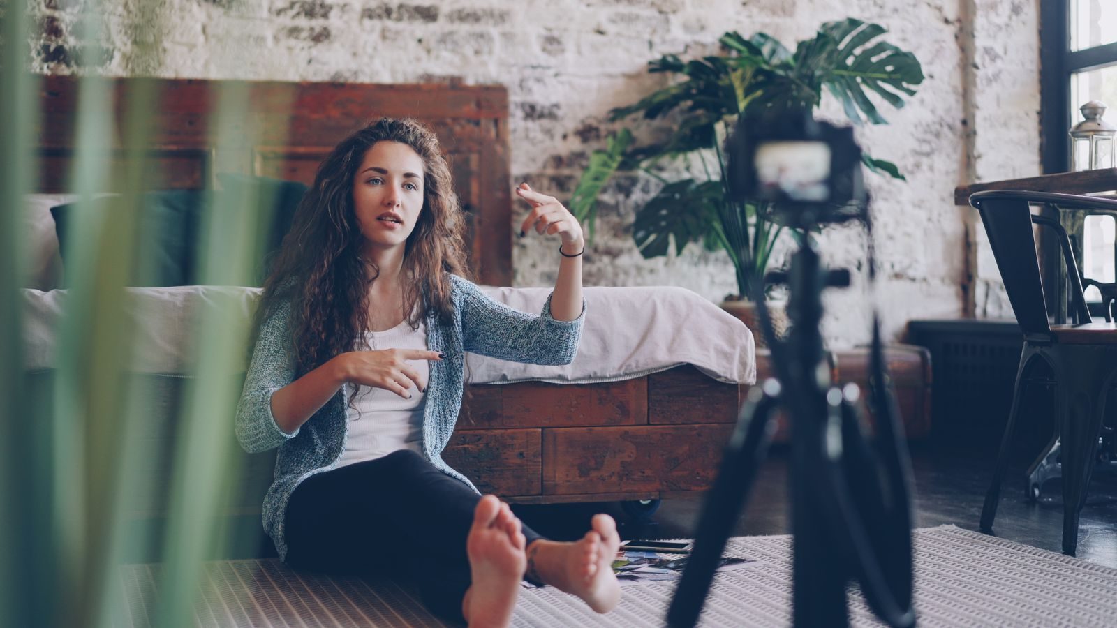 Mulher sentada no chão gravando vlog sobre um tema envolvente em casa aconchegante