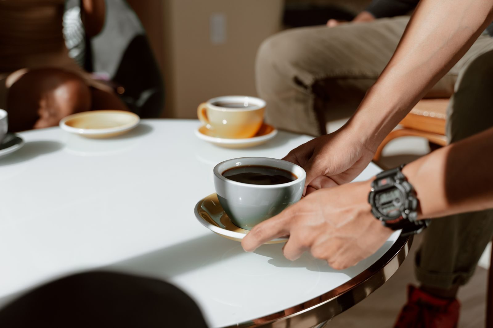 Pessoa servindo café em cafeteria estilosa com xícaras de cerâmica e clima de convívio