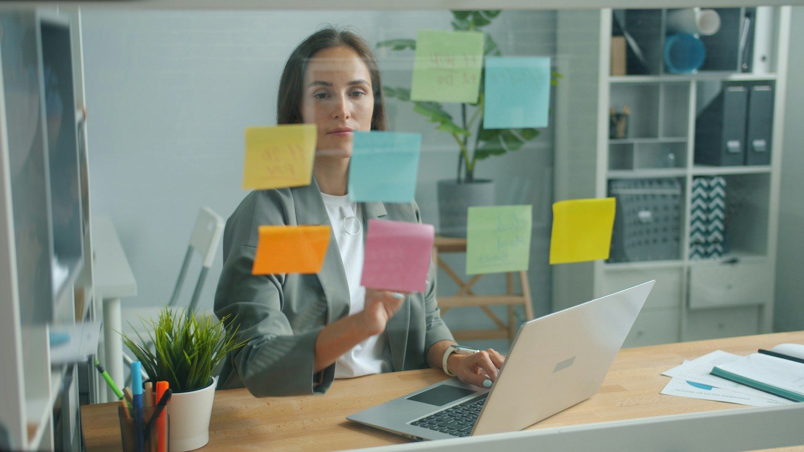 Mulher colando post-its em um quadro de vidro