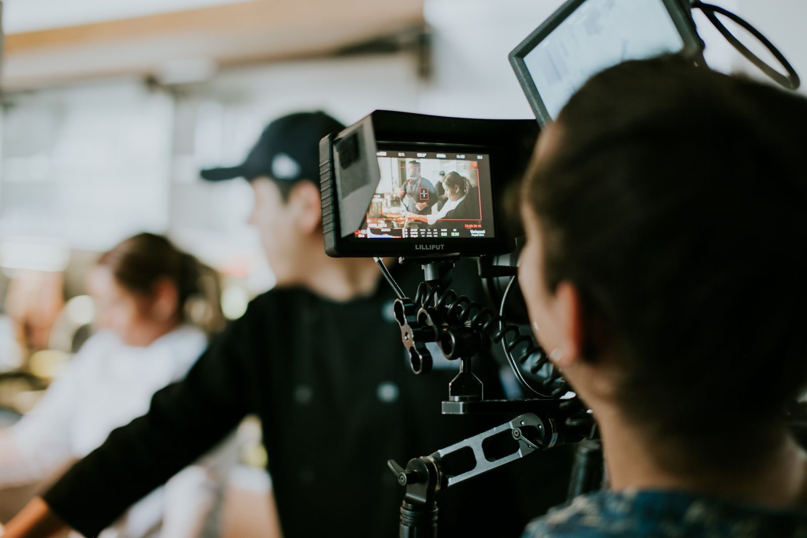 Bastidores de uma equipe de filmagem gravando uma cena, com foco em um monitor