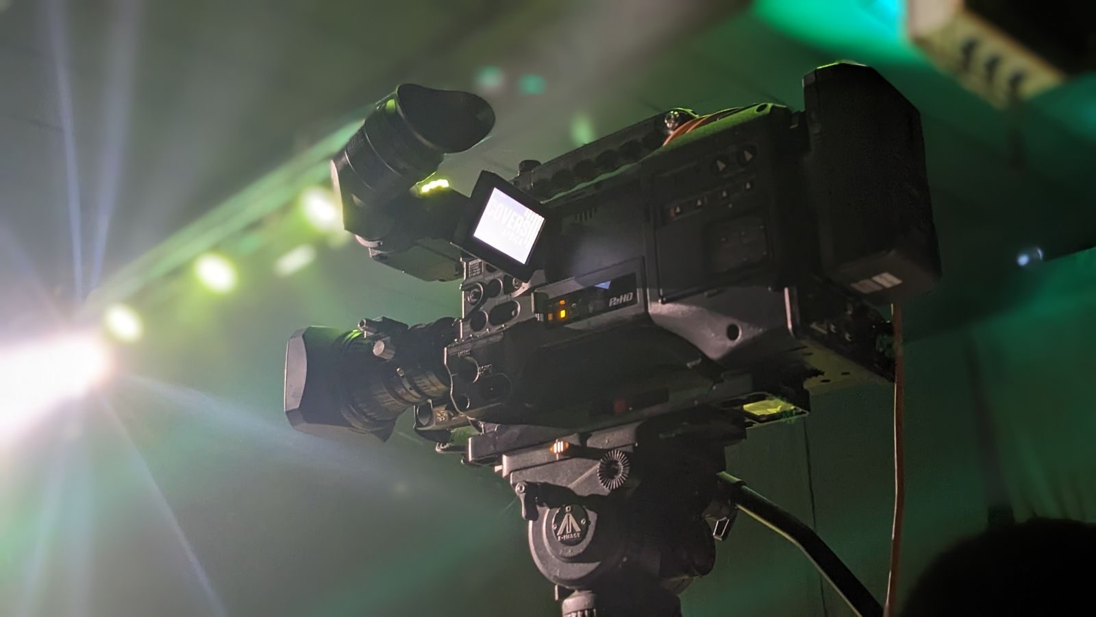 Close de uma câmera de vídeo profissional filmando um evento sob iluminação de palco